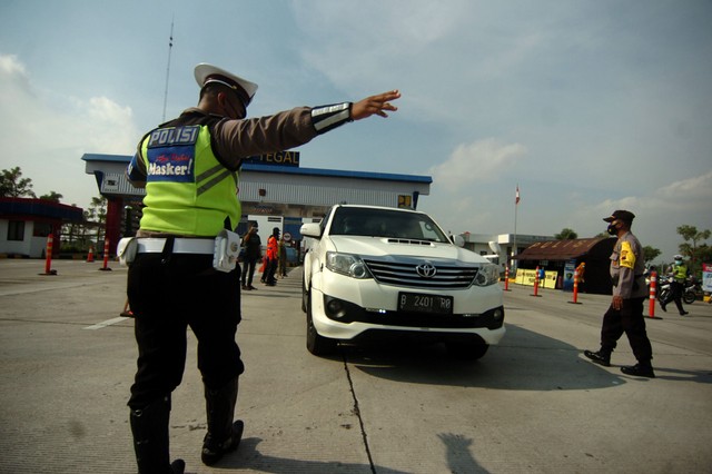 Personel kepolisian menghentikan sebuah mobil saat penyekatan mudik di pintu keluar Tol Tegal, Jawa Tengah. Foto: Oky Lukmansyah/ANTARA FOTO
