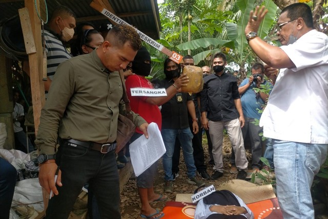 Adegan menghantam batu koral ke kepala korban dalam rekonstruksi kasus pembunuhan guru SMK di Aceh Barat. Foto: Siti Aisyah/acehkini