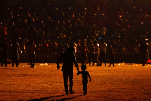 Seorang migran berjalan dengan seorang anak di sebuah stadion ketika mereka berharap untuk menerima bantuan dari pemerintah Meksiko untuk mendapatkan visa kemanusiaan untuk transit wilayah Meksiko. Foto: REUTERS/Jose Luis Gonzalez