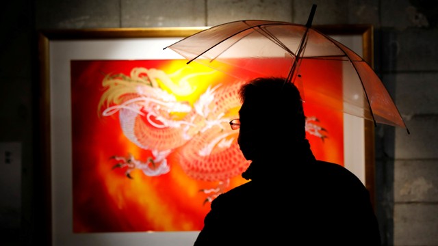 Seorang pengunjung memegang payung sambil melihat lukisan karya seniman Jepang Kazuhisa Kusaba di pameran seninya, di Tokyo Jepang, Jumat (3/12). Foto: Kim Kyung-Hoon/REUTERS