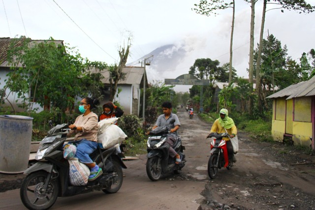 Warga bergegas menuju ke lokasi pengungsian saat awan panas dan debu vulkanik kembali meluncur dari kawah Gunung Semeru di Desa Supiturang, Pronojiwo, Lumajang, Jawa Timur, Senin (6/12/2021). Foto: Ari Bowo Sucipto/Antara Foto