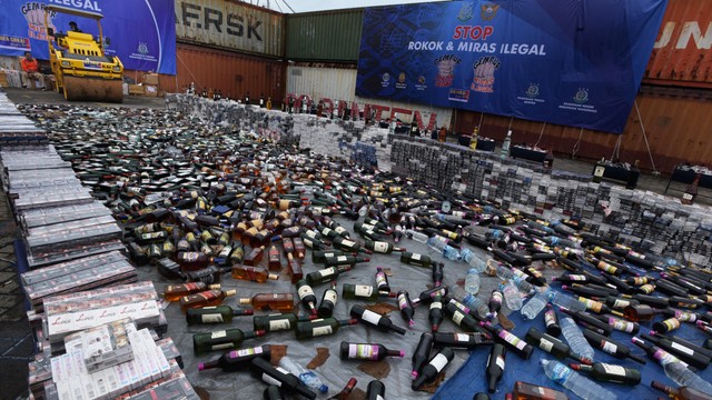 Petugas Kanwil Bea dan Cukai Banten menyiapkan alat berat untuk memusnahkan barang bukti ribuan botol minuman keras dan rokok ilegal di Merak, Banten, Selasa (7/12/2021). Foto: Asep Fathulrahman/ANTARA FOTO