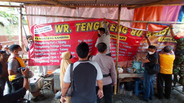 Paguyuban pedagang bersama polisi memasang spanduk berisi daftar harga di warung tengkleng yang viral di Solo Baru. FOTO: Fernando Fitusia