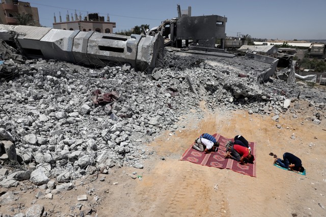 Jemaah Muslim Palestina salat di dekat puing-puing masjid yang hancur di Beit Lahia, di Jalur Gaza utara, pada 27 Mei 2021. Foto: Thomas Coex/AFP