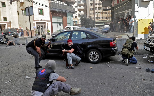 Pejuang dari gerakan Syiah Hizbullah dan Amal membidik selama bentrokan di daerah Tayouneh, di pinggiran selatan ibukota Beirut, pada 14 Oktober 2021. Foto: Anwar Amro/AFP