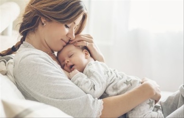 Ibu yang penuh kasih menggendong bayinya yang baru lahir di rumah. Potret cerah ibu bahagia memegang anak bayi yang sedang tidur di tangan. Ibu memeluk putra kecilnya yang berusia 2 bulan. (Alena Ozerova/Shutterstock.com)