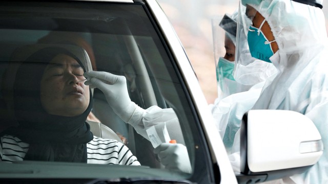 Petugas kesehatan yang mengenakan alat pelindung diri (APD) mengambil sampel swab untuk tes penyakit virus corona (COVID-19) di Jakarta. Foto: REUTERS/Ajeng Dinar Ulfiana