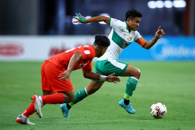 Pemain Timnas Indonesia Asnawi Mangkualam Bahar beraksi dengan pemain Singapura Nur Adam Abdullah pada semifinal Piala AFF Suzuki di Stadion Nasional Singapura, Rabu (22/12). Foto: Yong Teck Lim/Getty Images