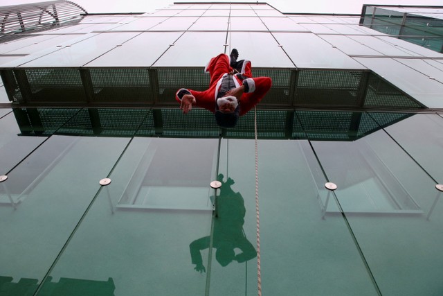 Seorang pemanjat berpakaian Sinterklas turun ke klinik pediatrik di Ljubljana, Slovenia. Foto: Borut Zivulovic/REUTERS