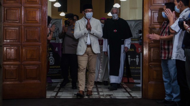 Gubernur Jawa Barat Ridwan Kamil (tengah) didampingi Pastor Leo van Beurden OSC (kanan) menyapa jemaat yang akan melaksanakan Misa Malam Natal 2021 di Gereja Katolik Katedral St. Petrus Bandung, Bandung, Jawa Barat, Jumat (24/12/2021). Foto: Novrian Arbi/ANTARA FOTO