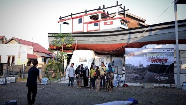 Warga berfoto di situs tsunami Kapal di Atas Rumah di Lampulo, Kota Banda Aceh, usai menyaksikan pameran foto dalam rangka peringatan 17 tahun tsunami Aceh. Foto: Abdul Hadi/acehkini  
