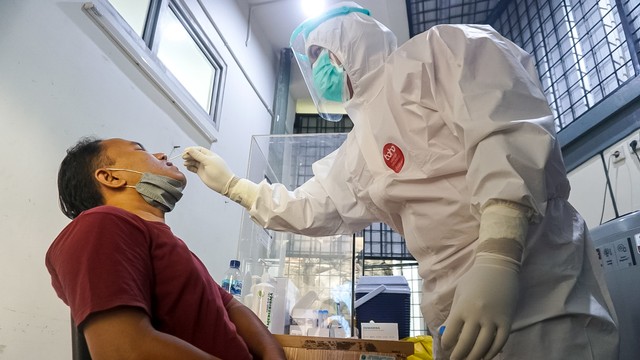 Petugas kesehatan melakukan tes swab kepada warga di pos screening Puskesmas Kecamatan Mampang Prapatan, Jakarta Selatan, Selasa (28/12/2021). Foto: Iqbal Firdaus/kumparan