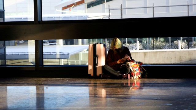 Seorang penumpang menunggu penerbangan setelah puluhan penerbangan terdaftar sebagai dibatalkan atau ditunda di Bandara Internasional Seattle-Tacoma (Sea-Tac) di Seattle, Washington, AS. Foto: Lindsey Wasson/REUTERS