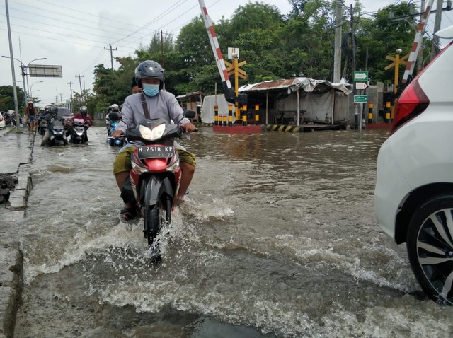 Pengendara sepeda motor melintasi  Jalan raya  Kaligawe Semarang yang terendam banjir. Foto: Intan Alliva/kumparan