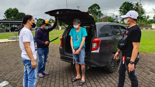 Pelaku penganiayaan menggunakan parang saat diamankan polisi di Kota Tomohon, Sulawesi Utara. (foto: istimewa)