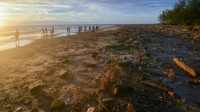 Sejumlah remaja bermain bola di antara sampah yang berserakan di Pantai Pasir Jambak, Padang, Sumatera Barat, Rabu (5/1/2022). Foto: Iggoy el Fitra/Antara Foto