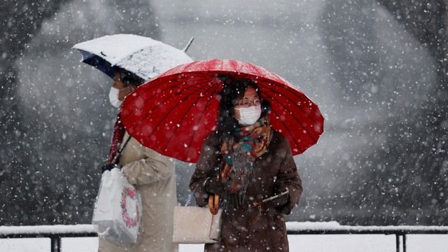 Sejumlah orang berjalan di tengah hujan salju, di Tokyo, Jepang, Kamis (6/1/2022). Foto: Issei Kato/REUTERS