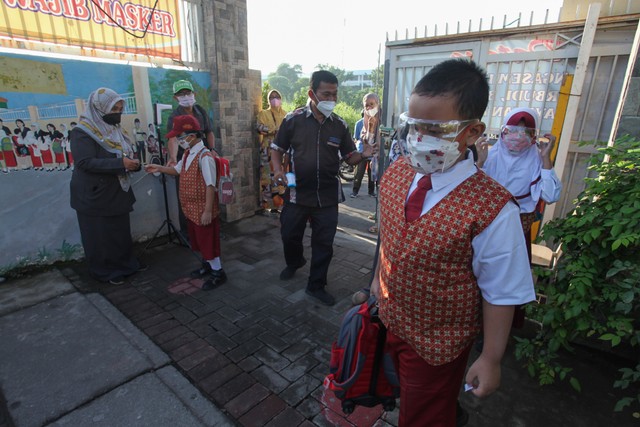 Sejumlah pelajar menjalani tes suhu badan sebelum masuk sekolah di SDN Klampis Ngasem I, Surabaya. Foto: ANTARA FOTO/Didik Suhartono