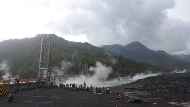 Warga melihat material lahar hujan Gunung Semeru mengalir di Kali Regoyo, Desa Sumberwuluh, Candipuro, Lumajang, Jawa Timur, Minggu (9/1/2022). Foto: Seno/Antara Foto