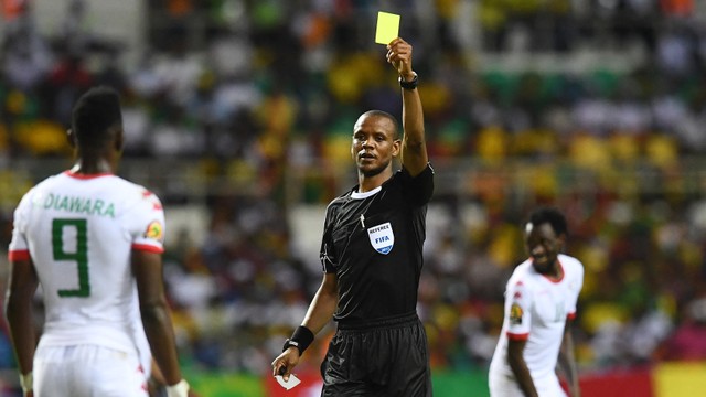Wasit Zambia Janny Sikazwe menunjukkan kartu kuning kepada pemain. Foto: Gabriel Bouys / AFP