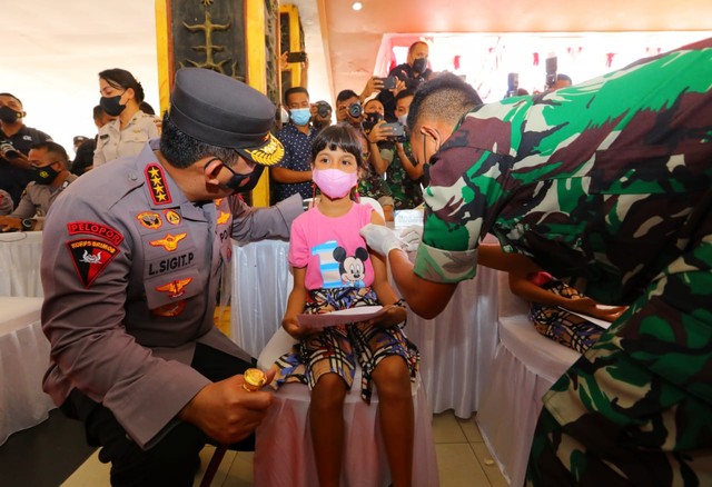 Kapolri Jenderal Listyo Sigit Prabowo menyapa anak saat meninjau akselerasi vaksinasi masal di Ambon, Maluku, Jumat (14/1). Foto: Dok. Polri