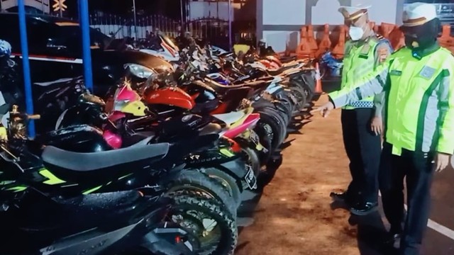 Petugas Polres Brebes menunjukkan puluhan sepeda motor berknalpot brong yang ditilang. (foto istimewa)