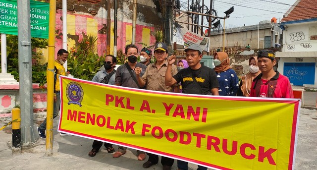 Sejumlah PKL Jalan Ahmad Yani didampingi aktivis membentangkan spanduk penolakan kebijakaan penggunaan food truck oleh Pemkot, di Jalan Ahmad Yani, Selasa (18/1/2022)