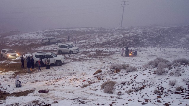 Warga Saudi bermain salju di Jabal al-Lawz (Gunung Almond), di sebelah barat kota Tabuk, Saudi, Senin (17/1/2022). Foto: Ibrahim ASSIRI/AFP 