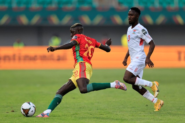 Pemain Guinea Pa Konate berusaha melewati pemain Gambia Ablie Jallow pada pertandingan 16 besar Piala Afrika 2021 di Stade de Kouekong, Bafoussam, Kamerun, Senin (24/1/2022).  Foto: Thaier Al-Sudani/REUTERS