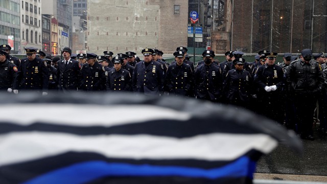 Petugas polisi berdiri dengan bendera 'Blue Lives Matter' selama upacara pemakaman Jason Rivera di Katedral St. Patrick di wilayah Manhattan, New York City, AS , Jumat (28/1/2022). Foto: Jeenah Moon/REUTERS