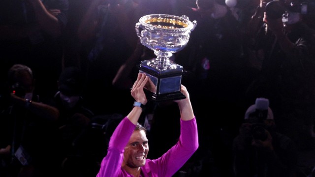 Petenis Spanyol Rafael Nadal merayakan kemenangannya di final tunggal putra dengan trofi pada Australia Open 2022, Senin (31/1/2022). Foto: Loren Elliott/REUTERS