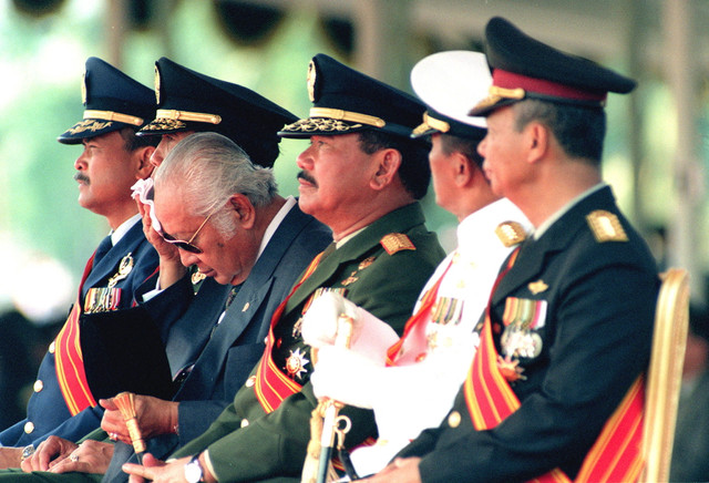 Presiden Indonesia Suharto (tengah) menyeka keringatnya saat menyaksikan perayaan HUT ke-50 Angkatan Bersenjata Republik Indonesia (ABRI) di Lanud Halim Perdanakusuma, 05 Oktober 1995. Foto: MACDOUGALL / AFP