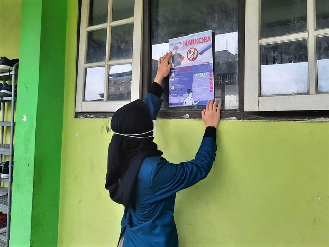 Mahasiswa menempel poster Sosialisasi Narkoba di jendela kelas MTs Infarul Ghoy Semarang (Sumber: Pribadi)