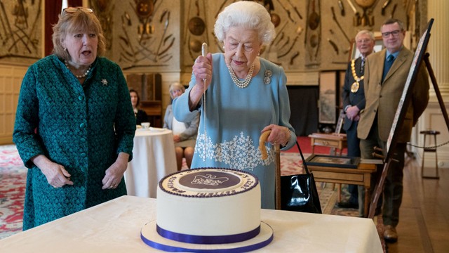 Ratu Elizabeth II Inggris memotong kue untuk merayakan Platinum Jubilee di Ballroom Sandringham House, Inggris, Sabtu (5/2/2022). Foto: Joe Giddens/Reuters