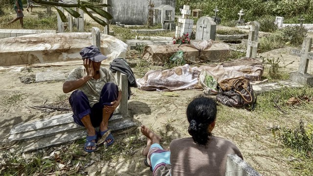 Warga melihat kuburan kerabat yang rusak akibat topan Batsirai di pemakaman lokal di Mahanoro, Madagaskar, Minggu (6/2/2022). Foto: Laure Verneau / AFP
