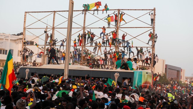 Penggemar Senegal merayakan dan menunggu untuk menyambut Tim Sepak Bola Nasional Senegal saat mereka tiba setelah kemenangan Piala Afrika mereka, di Dakar, Senegal 7 Februari 2022. Foto: REUTERS/Zohra Bensemra