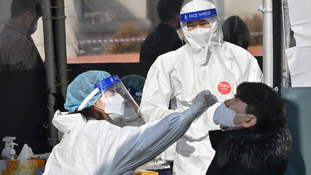 Sejumlah tenaga medis mengambil sampel swab masyarakat di pusat pengujian virus di Seoul, Korea Selatan, Rabu (9/2/2022). Foto: Jung Yeon-je / AFP