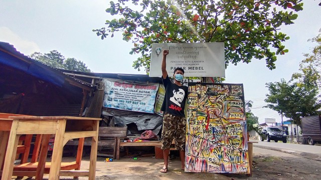 Pedagang Pasar Mebel, Solo memegang papan mural di halaman pasar tersebut, Rabu (09/02/2022). FOTO: Tara Wahyu