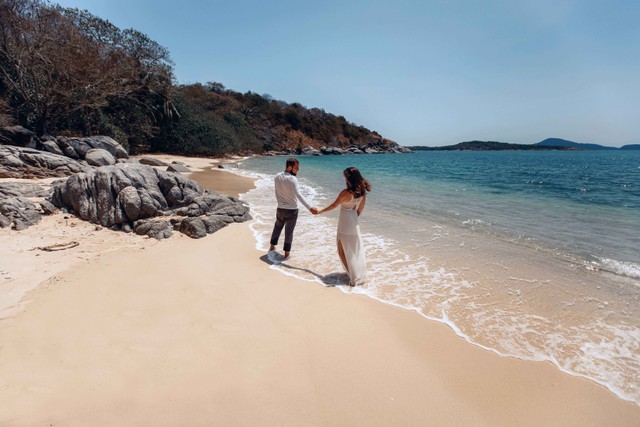 Pasangan bergandengan tangan di pantai. Foto: Semachkovsky/Shutterstock