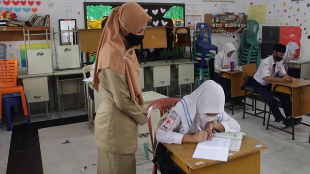 SEORANG guru memperhatikan siswi SMP di Pekanbaru belajar di masa pandemi COVID-19. 