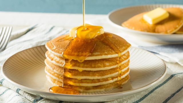 Tumpukan pancake madu lembut yang disajikan dengan siraman madu dan buah segar, sempurna untuk sarapan atau camilan